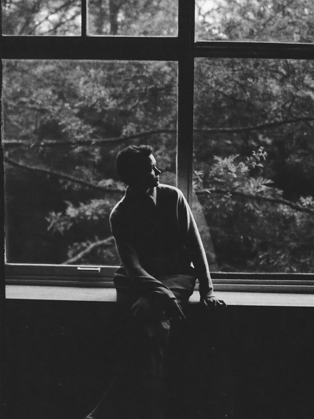 A person sitting alone by a window, reflecting